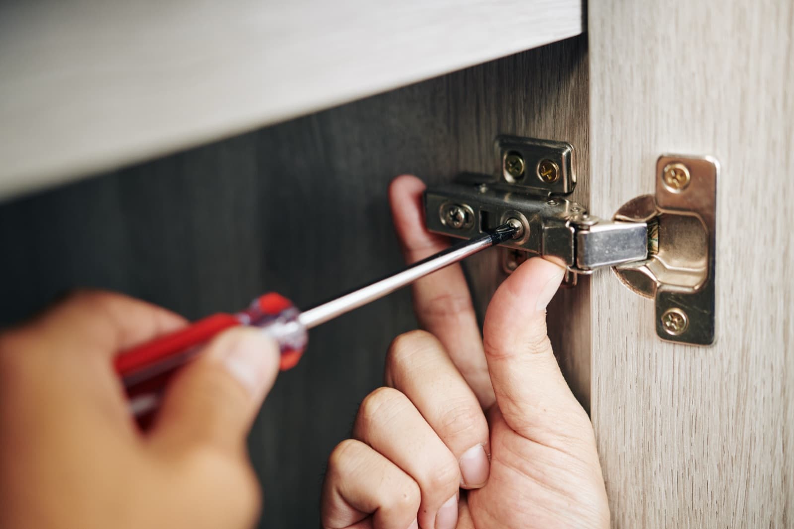 Handyman repairing a kitchen cabinet hinge